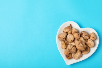 Plate with dried figs on color background, top view with space for text. Healthy fruit