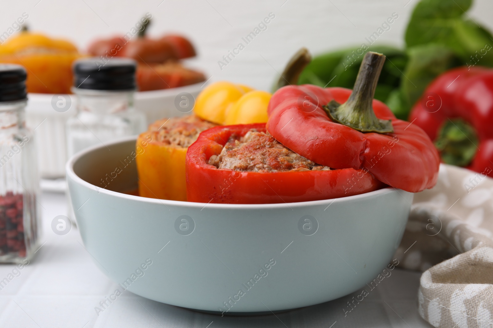 Photo of Delicious stuffed bell peppers on white tiled table, closeup