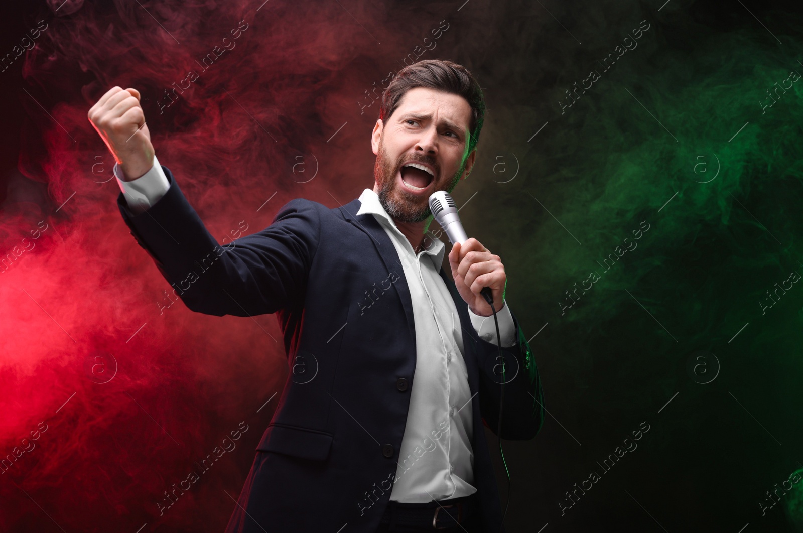 Photo of Emotional man with microphone singing in color lights