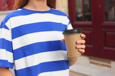 Coffee to go. Woman with paper cup of drink outdoors, closeup