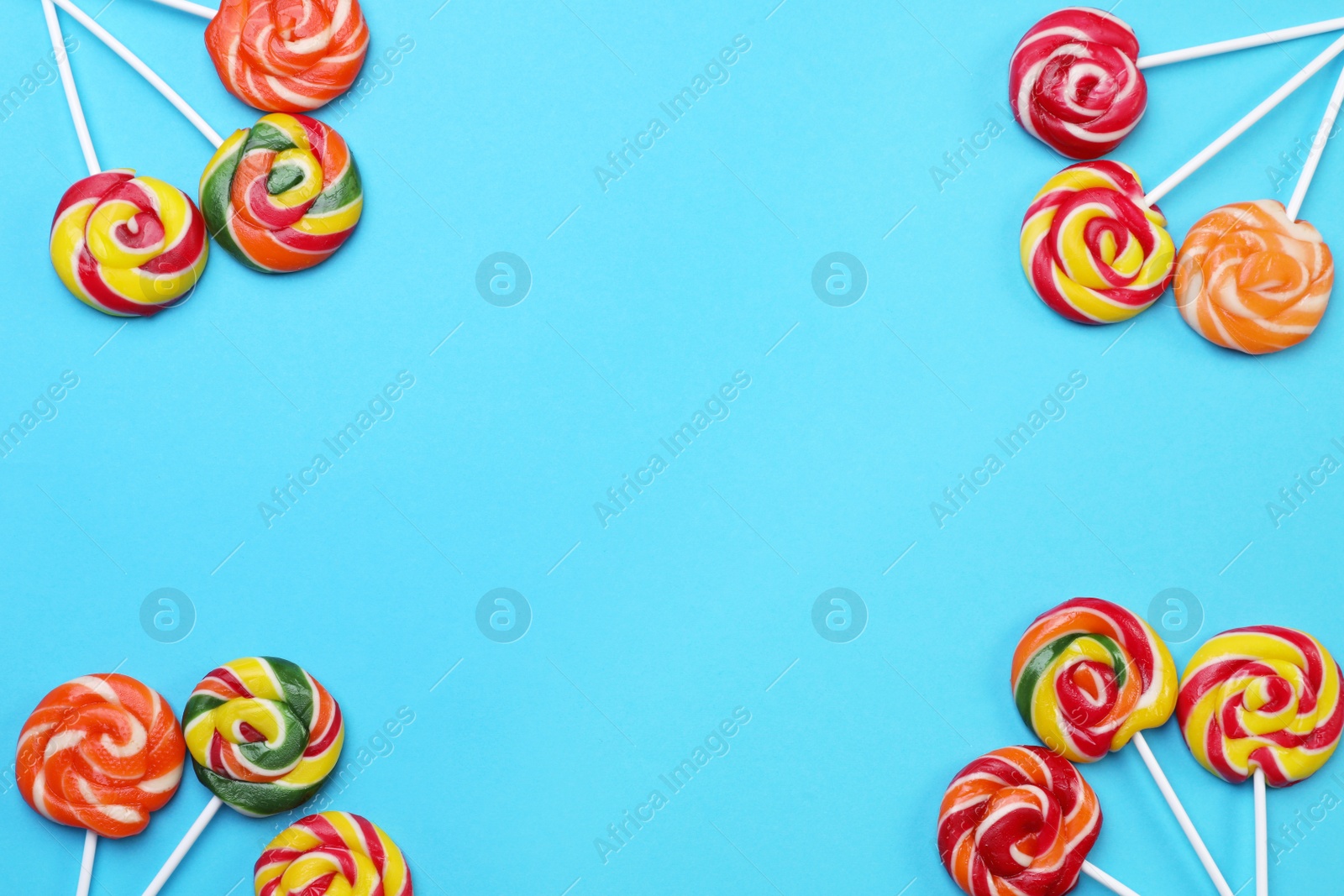 Photo of Sweet lollipops on light blue background, flat lay. Space for text