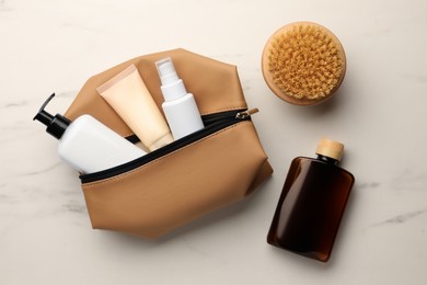 Preparation for spa. Compact toiletry bag and different cosmetic products on white marble table, flat lay