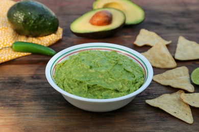 Photo of Delicious guacamole made of avocados with nachos on wooden table