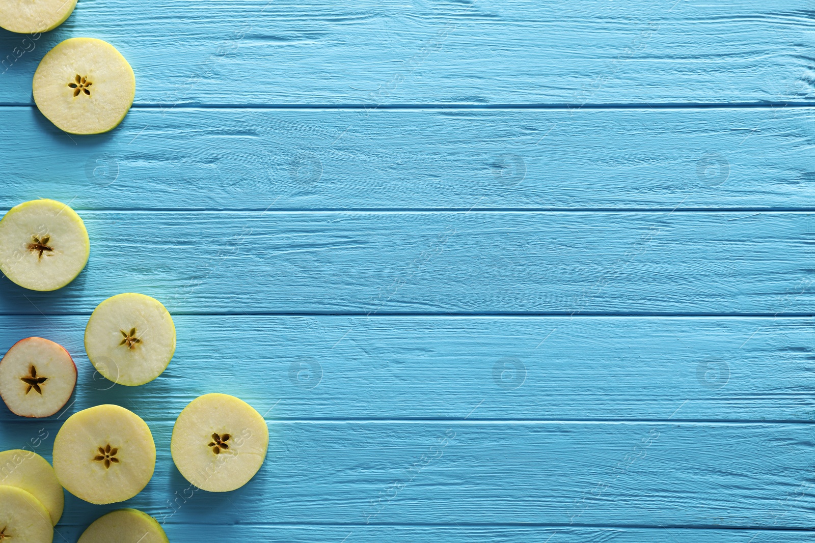 Photo of Food photography. Slices of apple on light blue wooden table, flat lay with space for text
