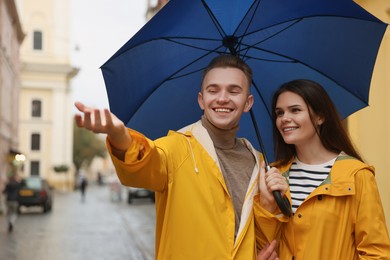 Photo of Lovely young couple with umbrella walking under rain on city street
