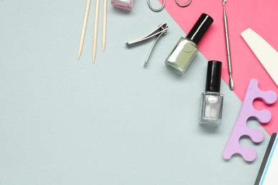 Photo of Nail polishes and set of pedicure tools on color background, flat lay. Space for text