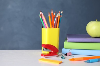 Photo of Apple and different school stationery on white wooden table