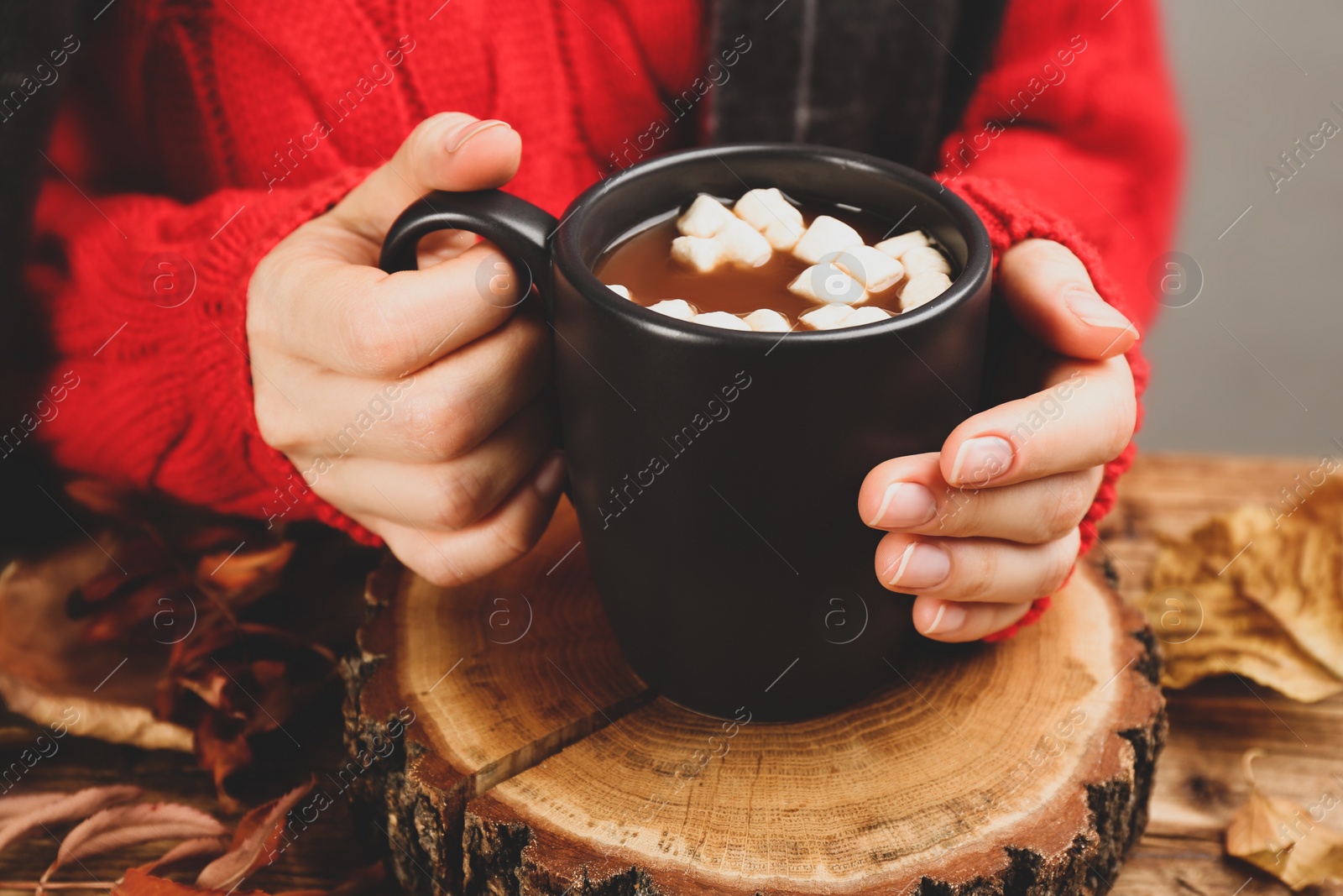 Photo of Woman with cup of hot drink at wooden table, closeup. Cozy autumn atmosphere