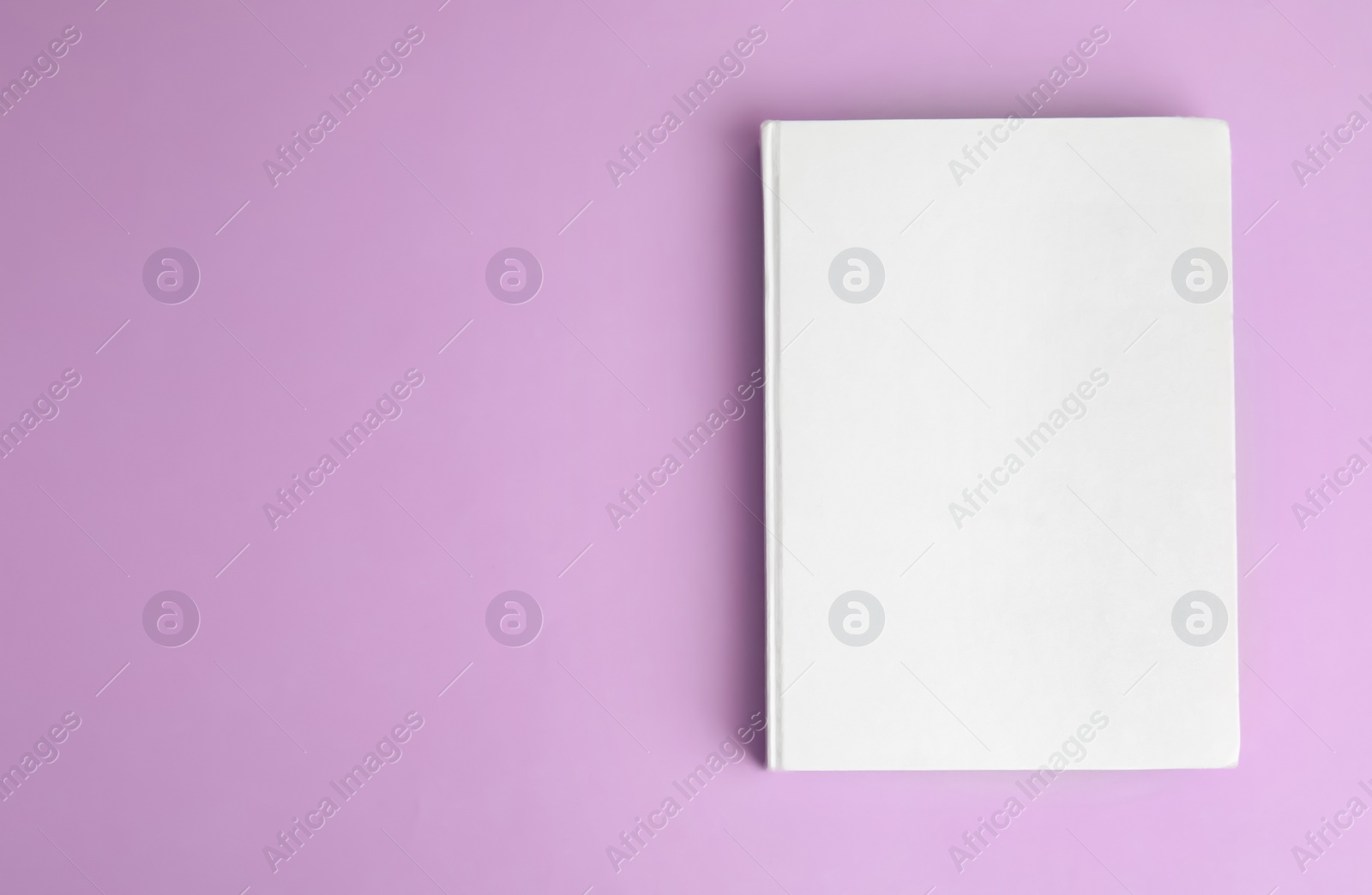 Photo of Book with blank cover on violet background, top view. Space for text