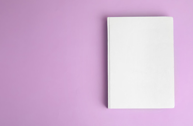 Photo of Book with blank cover on violet background, top view. Space for text