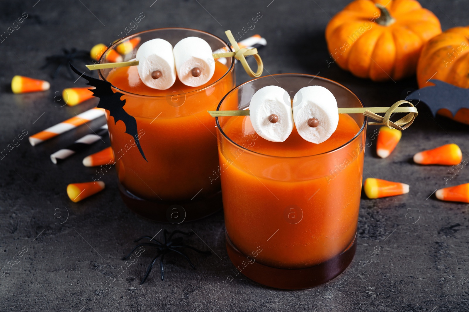 Photo of Decorated glasses with drinks on grey table. Halloween celebration