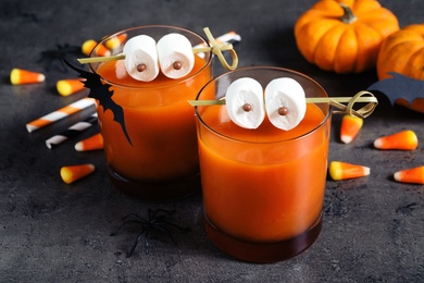 Decorated glasses with drinks on grey table. Halloween celebration