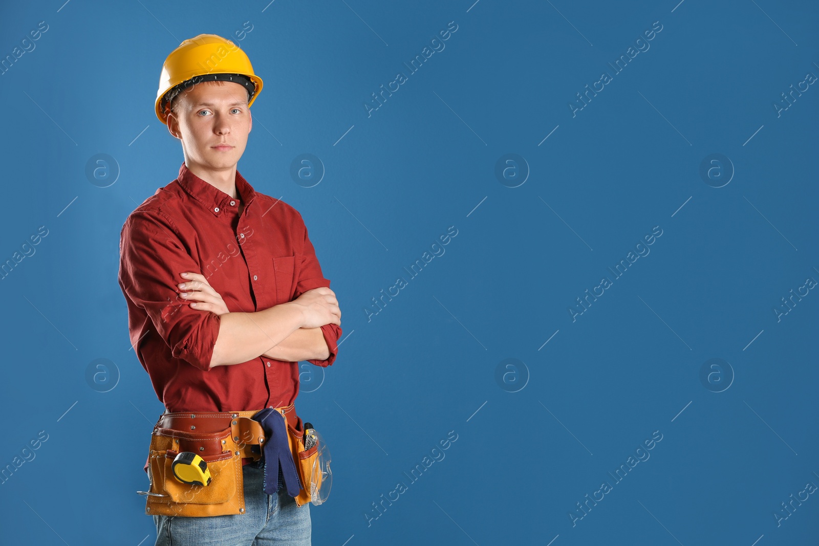 Photo of Handsome young working man in hard hat against color background, space for text