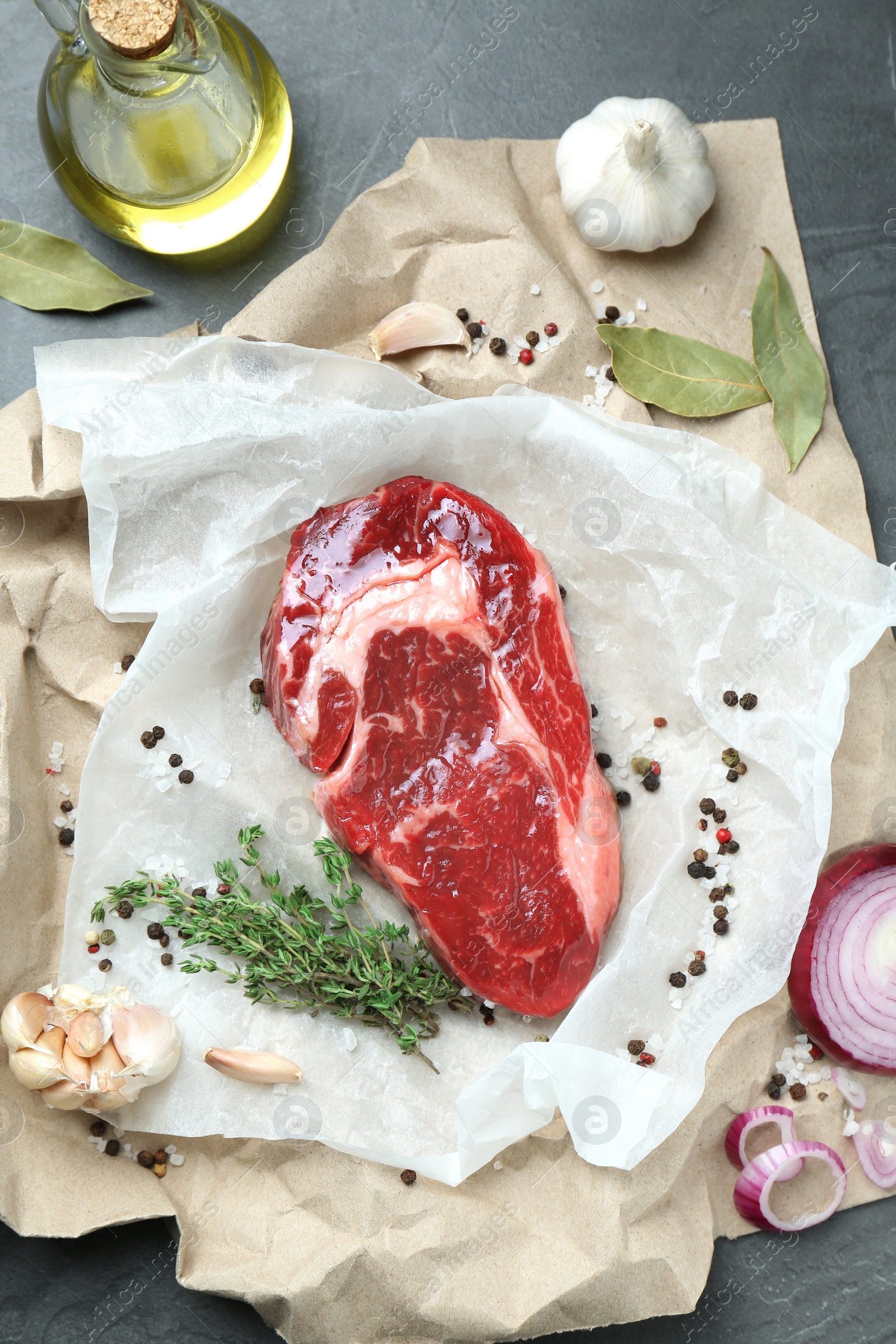 Photo of Piece of raw beef meat and spices on grey table, flat lay