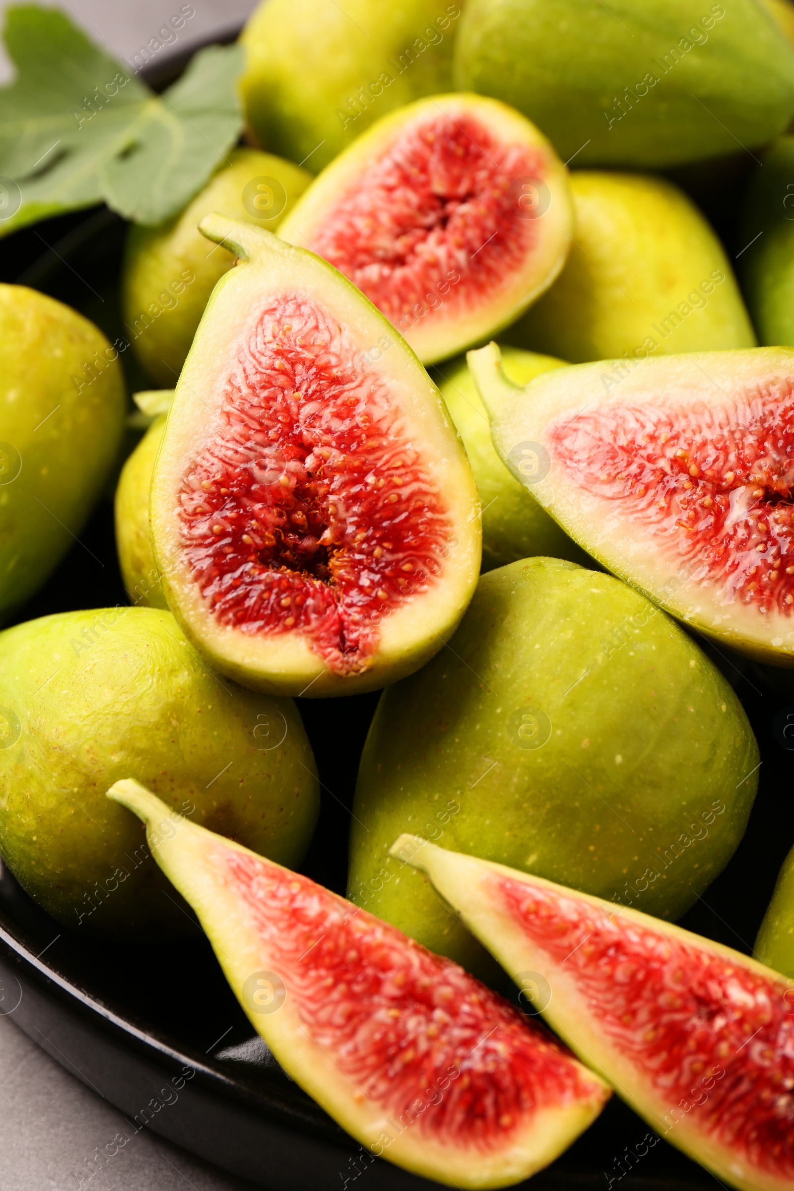 Photo of Cut and whole green figs on plate, closeup