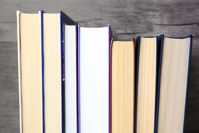 Photo of Collection of different books near wooden wall, closeup