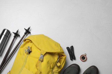 Photo of Flat lay composition with trekking poles and other hiking equipment on light background, space for text