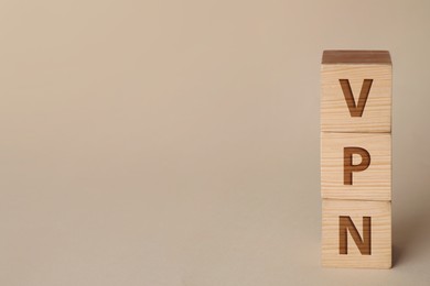 Wooden cubes with acronym VPN on beige background. Space for text