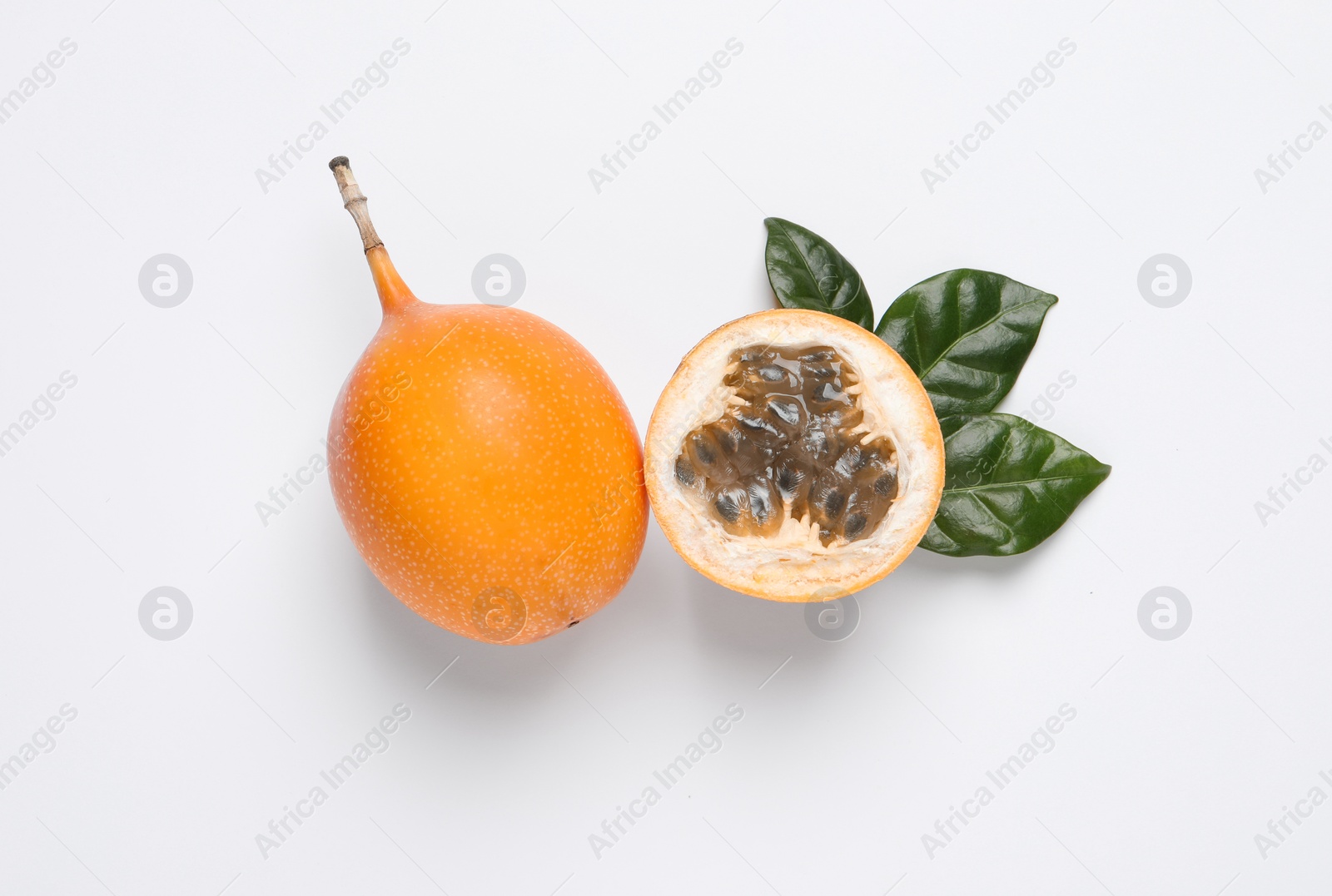 Photo of Delicious ripe granadillas with leaves on white background, flat lay