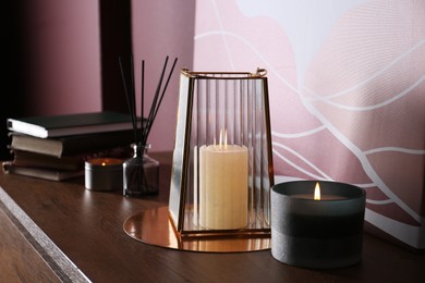 Burning scented candles on wooden table indoors