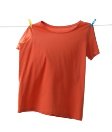 Photo of One orange t-shirt drying on washing line isolated on white