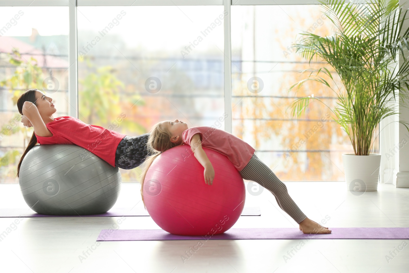 Photo of Woman and daughter doing exercise with fitness balls at home