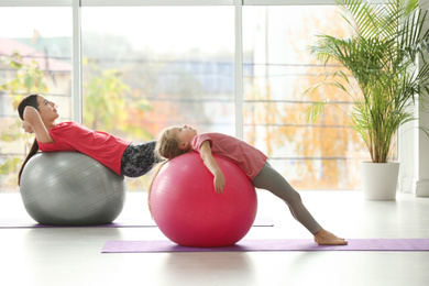 Woman and daughter doing exercise with fitness balls at home