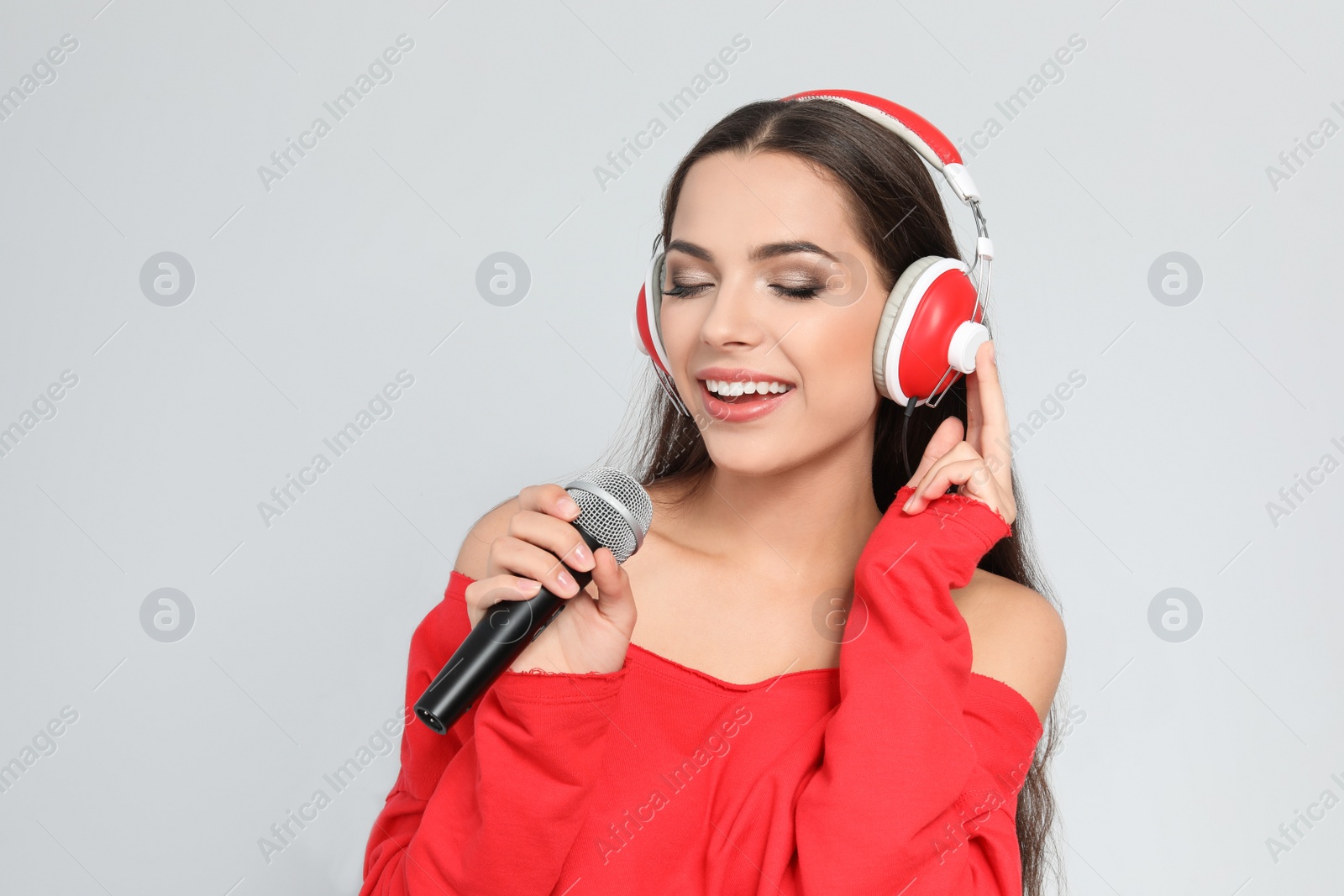 Photo of Young woman singing into microphone on color background. Christmas music