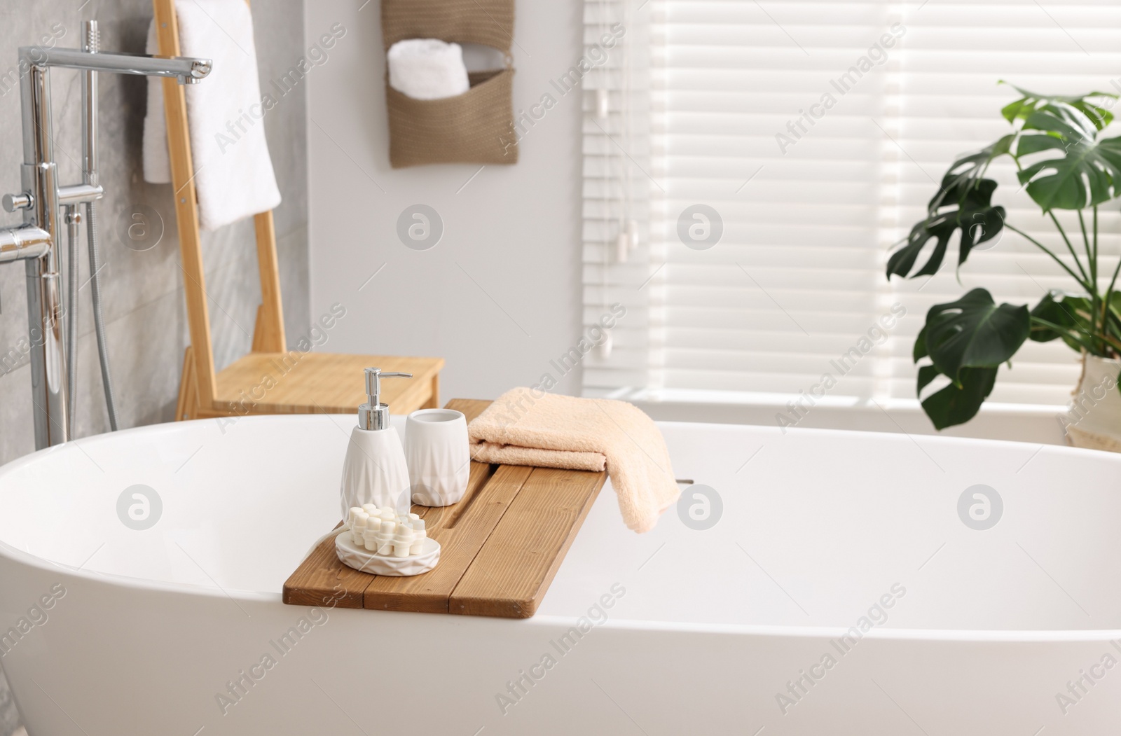 Photo of Set of different bath accessories and soap on tub in bathroom