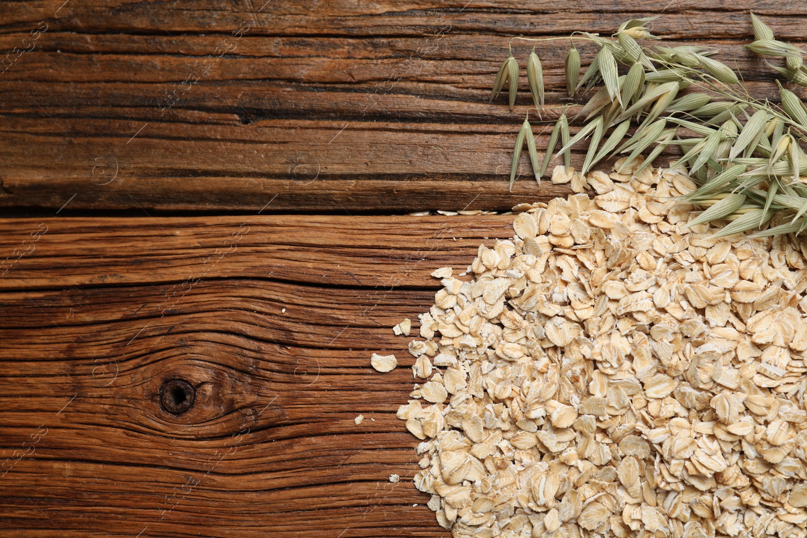 Photo of Oatmeal and branches with florets on wooden table, flat lay. Space for text