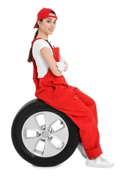 Female mechanic in uniform with car tire on white background