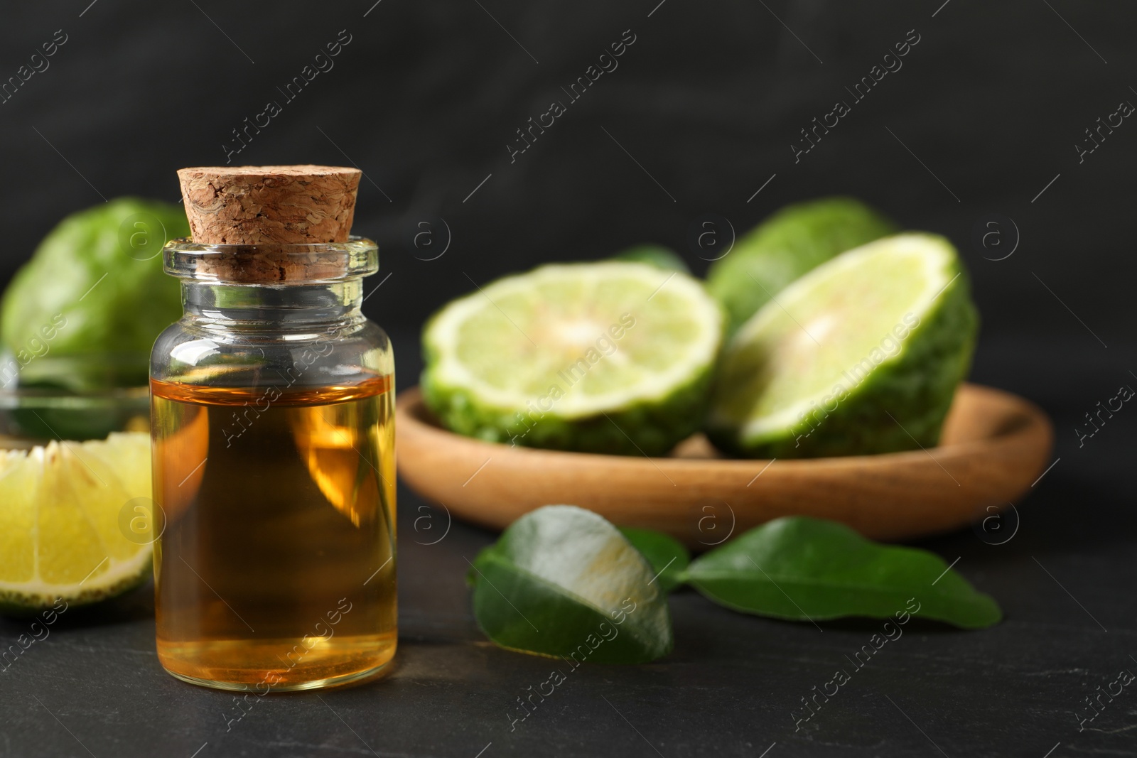 Photo of Bottle of bergamot essential oil on dark table, closeup. Space for text