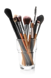 Photo of Glass with makeup brushes of professional artist on white background