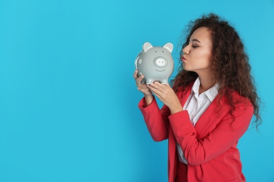 African-American businesswoman with piggy bank on color background, space for text. Money saving