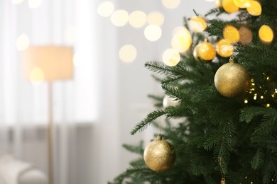 Photo of Christmas balls hanging on fir tree indoors, closeup. Space for text