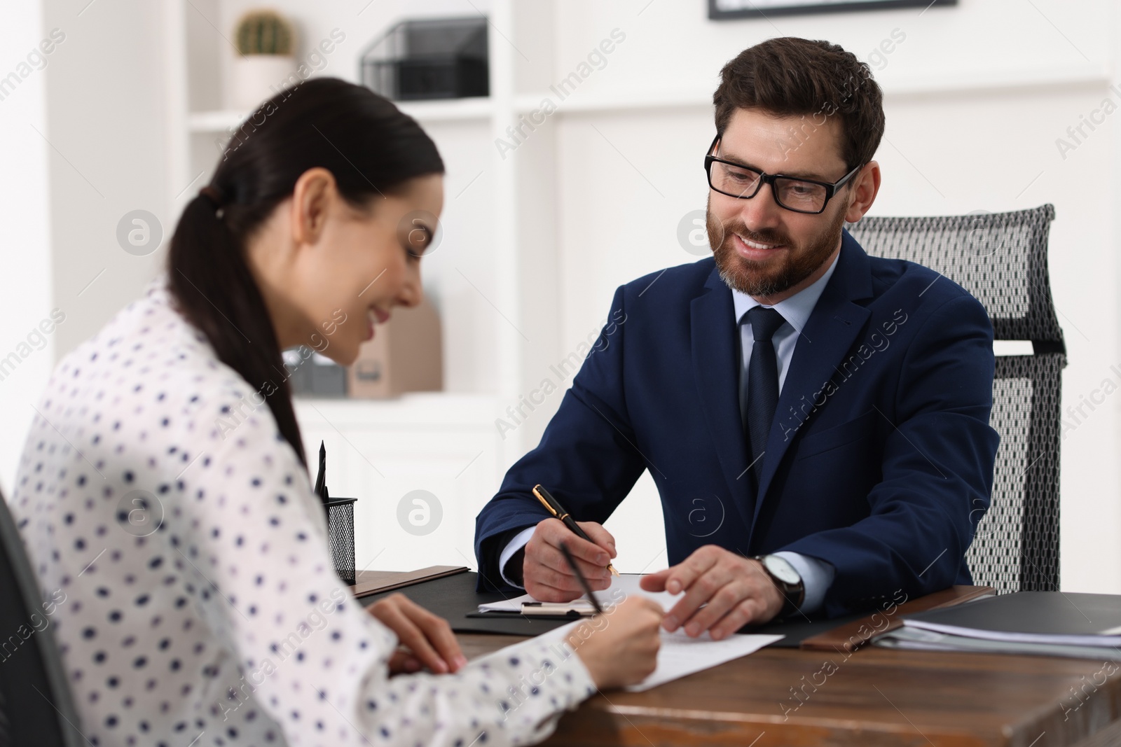 Photo of Woman signing document in lawyer's office, selective focus