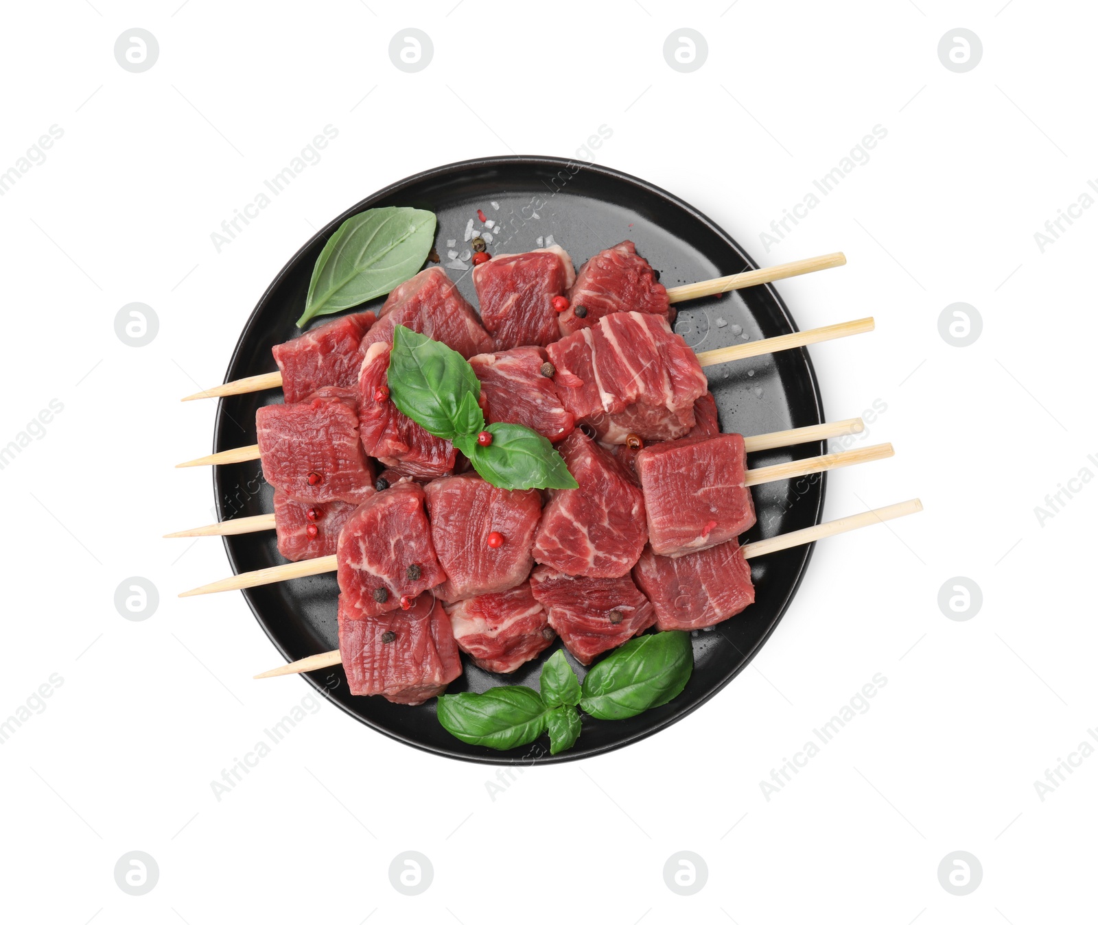 Photo of Wooden skewers with cut fresh beef meat, basil leaves and spices isolated on white, top view