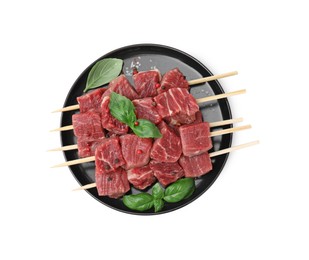 Wooden skewers with cut fresh beef meat, basil leaves and spices isolated on white, top view