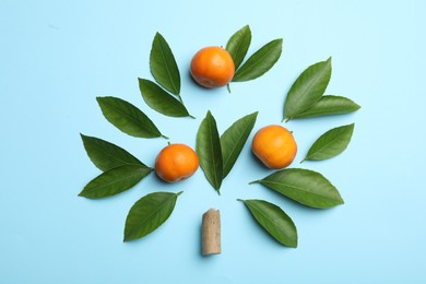 Photo of Flat lay composition with fresh green citrus leaves and tangerines on light blue background