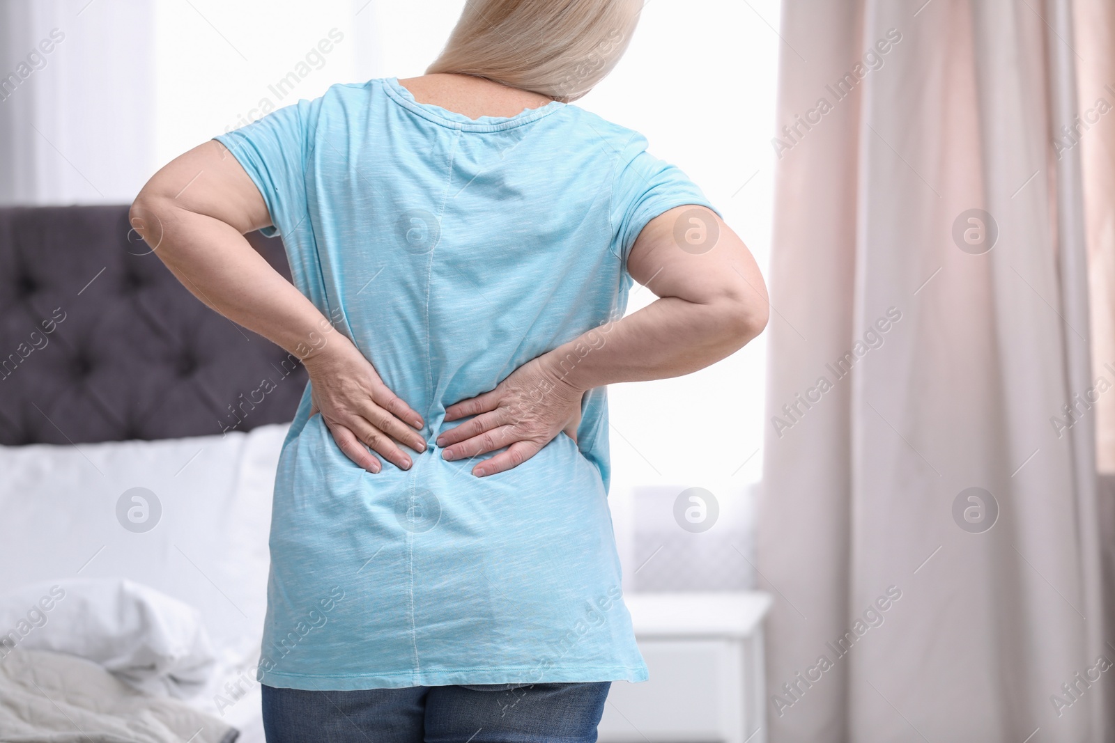 Photo of Senior woman suffering from back pain at home, closeup