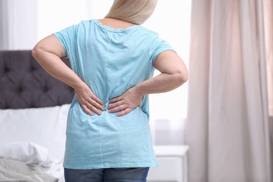 Senior woman suffering from back pain at home, closeup