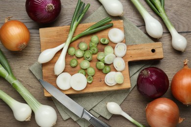 Different kinds of onions on wooden table, flat lay