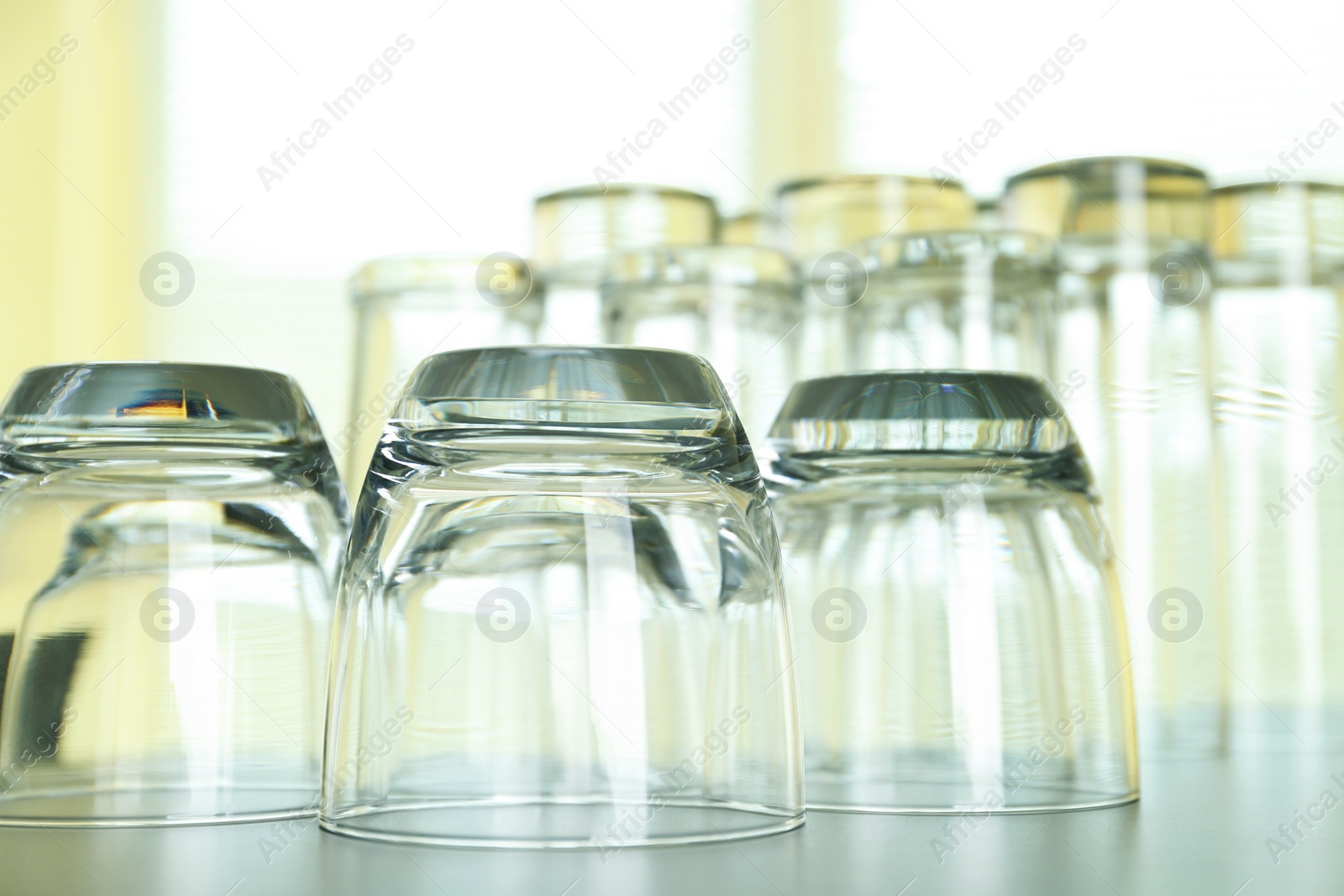 Photo of Empty glasses on grey table against blurred background, closeup