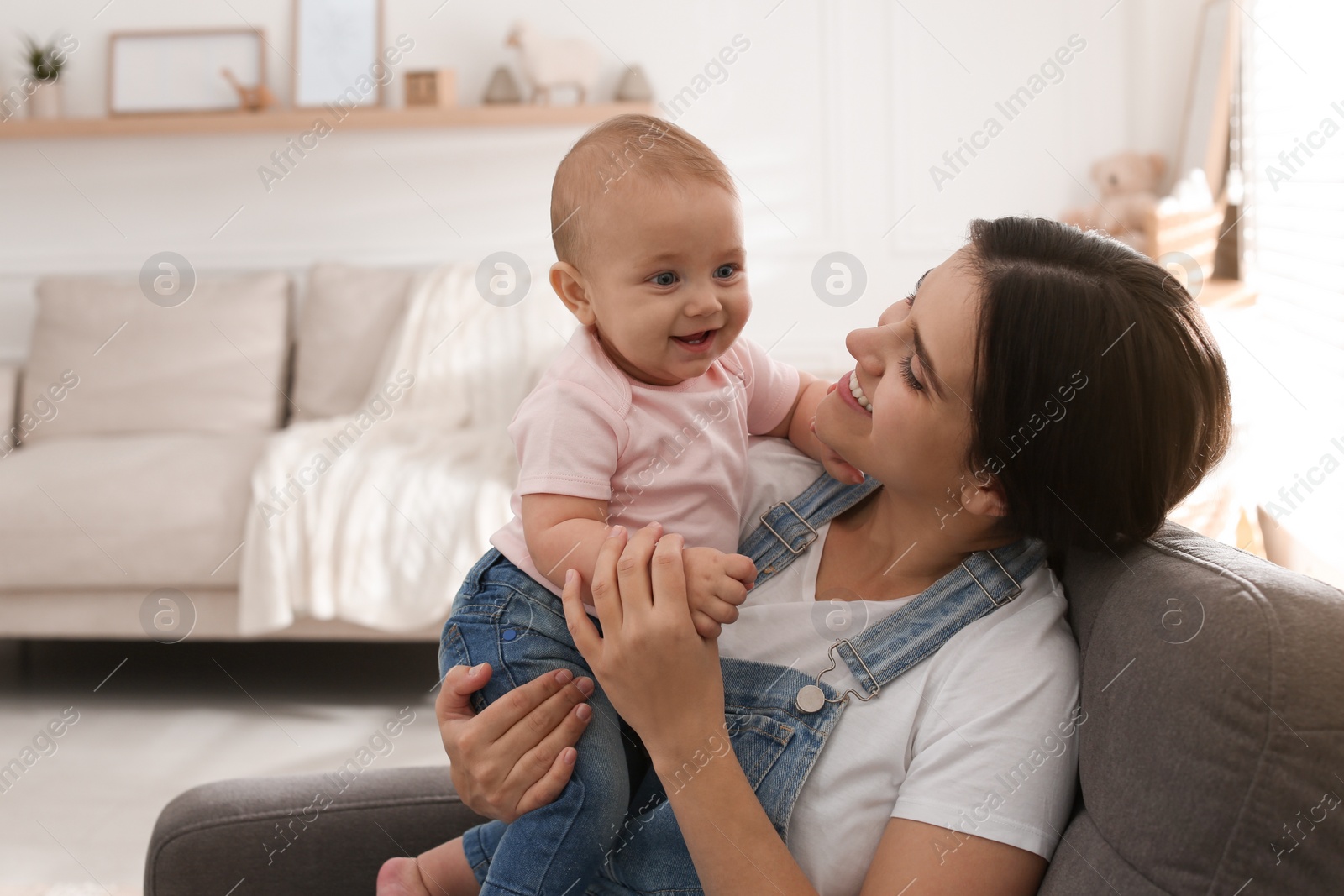 Photo of Happy young mother with her cute baby in armchair at home