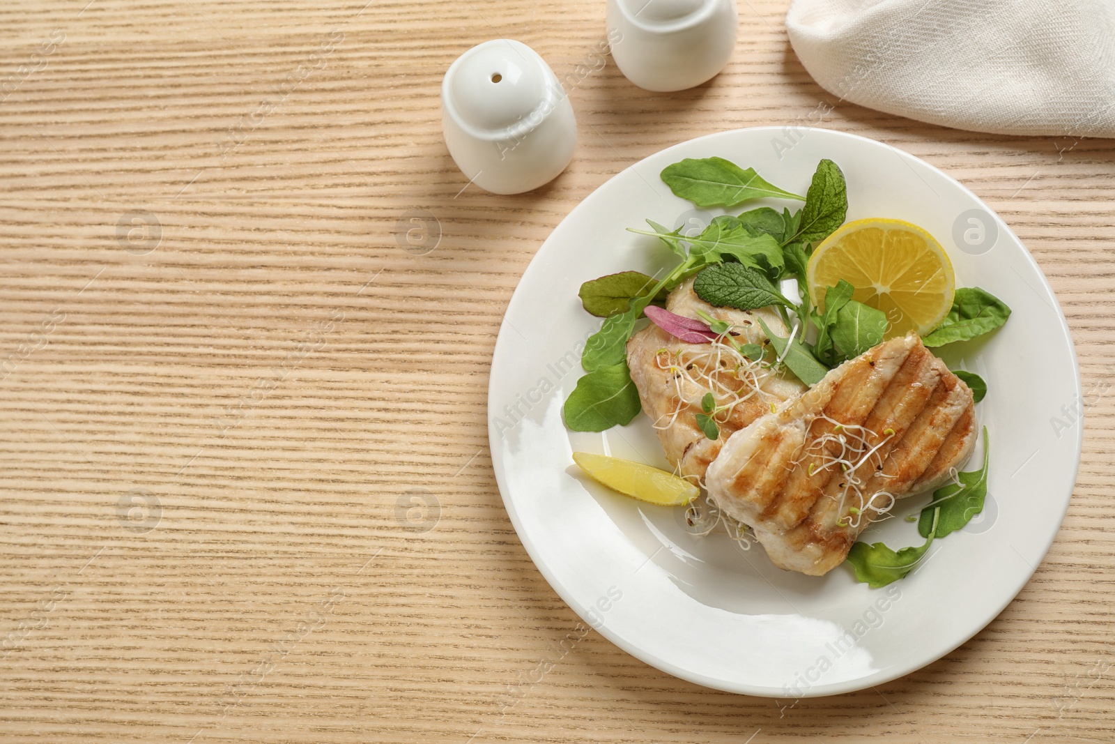 Photo of Tasty grilled fish served on wooden table, flat lay. Space for text