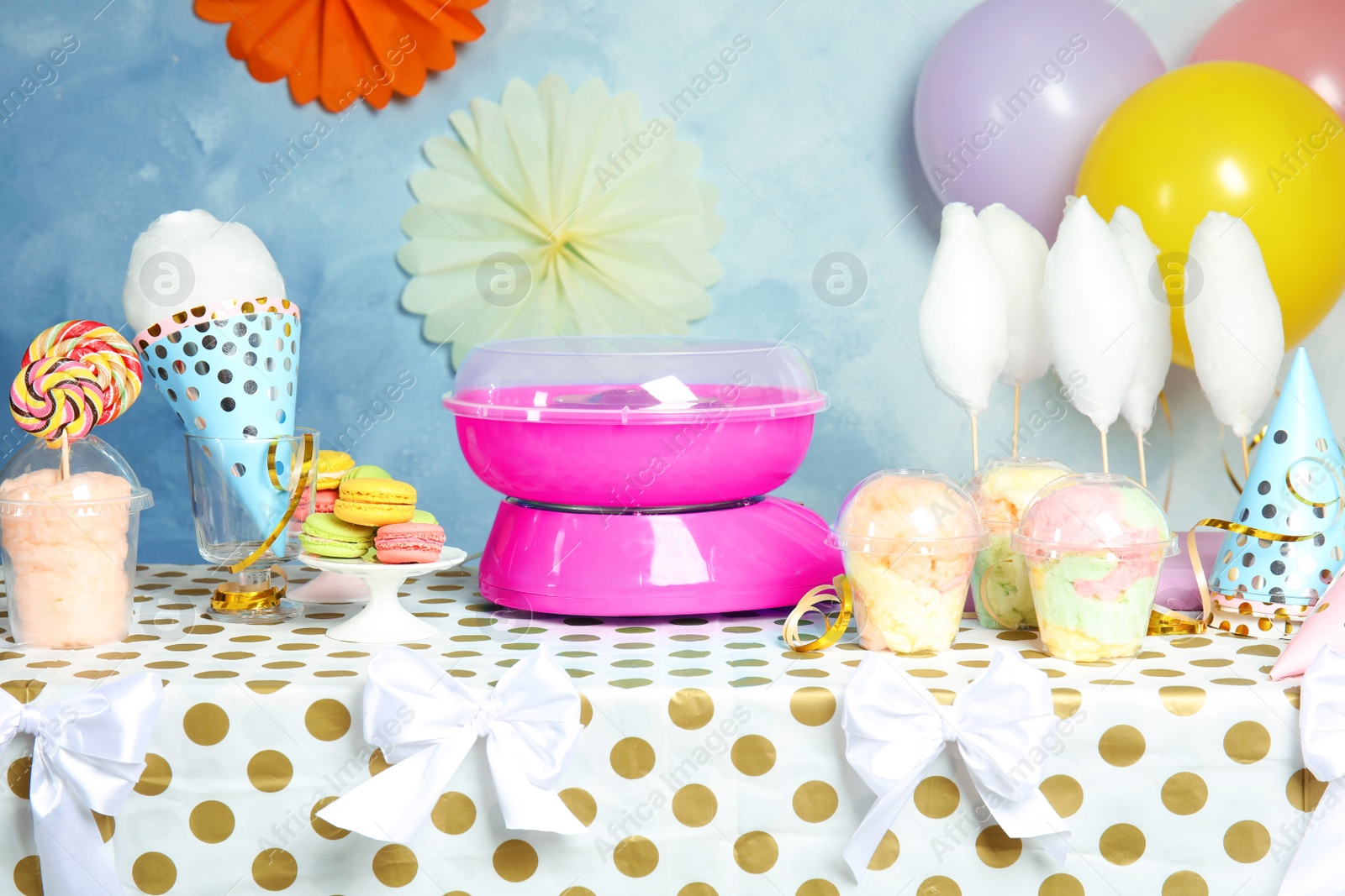 Photo of Cotton candy machine and treats on table at party