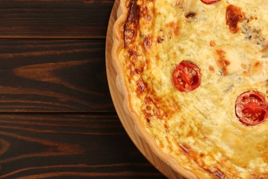 Photo of Delicious quiche with cheese and tomatoes on wooden table, top view. Space for text