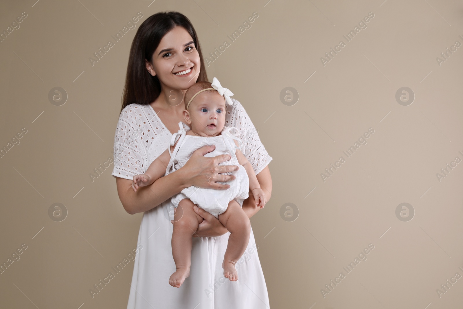 Photo of Beautiful mother with her cute baby on beige background. Space for text