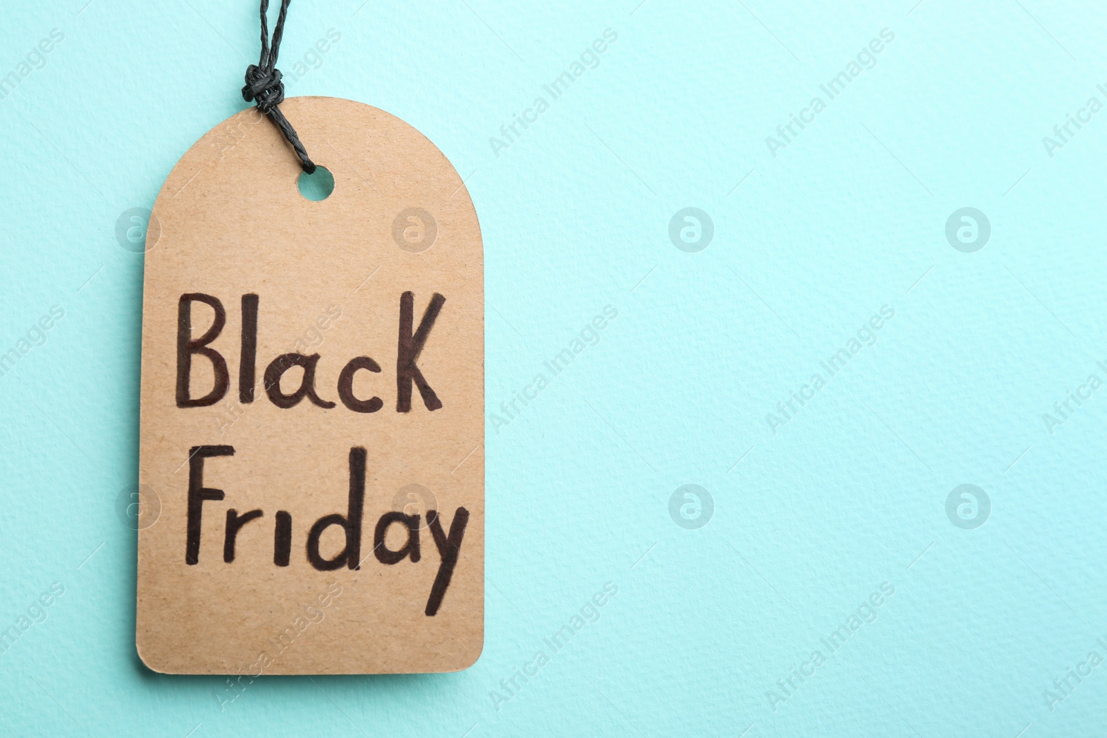 Photo of Tag with words BLACK FRIDAY on turquoise background, top view. Space for text