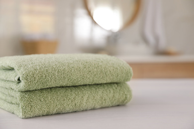 Photo of Stack of clean towels on white wooden table in bathroom